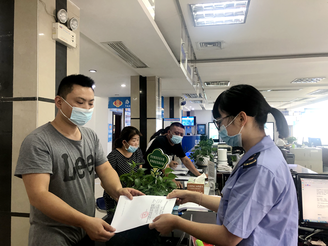 图为县市场监管局窗口工作人员发放《仅销售预包装食品备案回执》.png